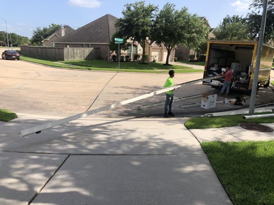Long seamless gutter section being handled near a home